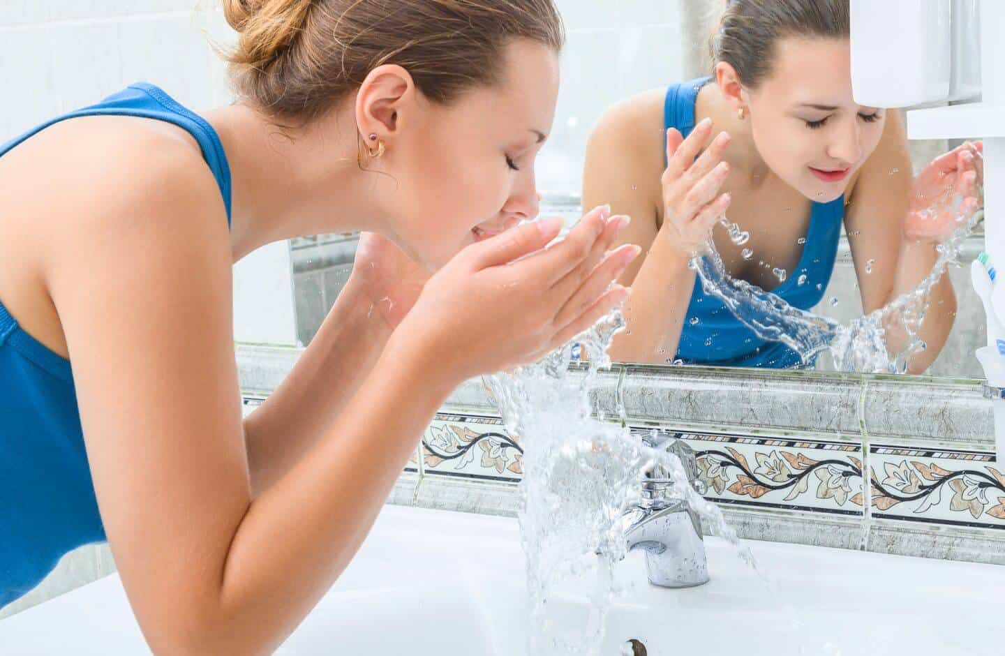Woman cleaning face with softer, healthier water from a home water softener system