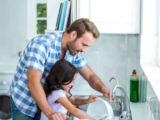 Father and daughter washing dishes with cleaner, healthier water from whole house water filtration system
