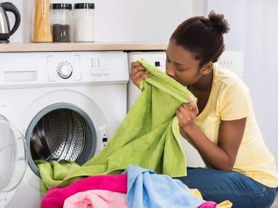 Woman enjoying the smell of cleaner, softer laundry from washing machine on a home water softener system